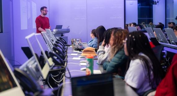Photo of adult students in a computer classroom, with an instructor at the front