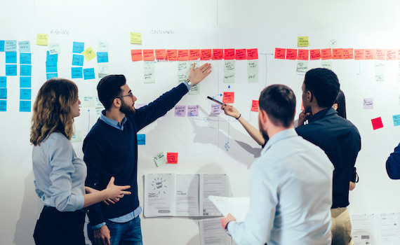 A work team organizing sticky notes on a whiteboard