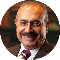 Older business man with glasses wearing a brown suit, white top and red tie