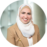 Headshot of Houda, a woman in a floral print Hijab and blazer