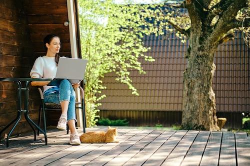 Photo of a woman working outside with her laptop on a sunny day