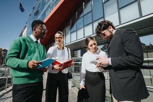 A group of four professionals discussing outside on a sunny day