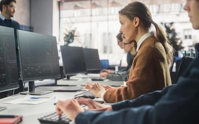 Three business people working at a desk with computers