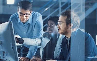 group of three employs looking at a computer screen and discussing