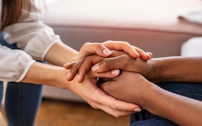 the hand of a white woman and black woman holding hands