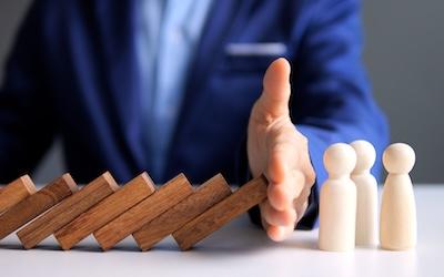 Photo of business person  blocking with their hands dominoes falling over