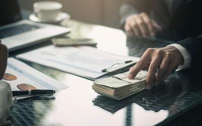 Photo of a business person handing over a wad of money 