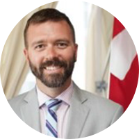 Photo of a white business man with a grey suit, pink button up and a stripped tie