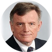 photo of an older white business man wearing a black suit and white button up with a patterned tie