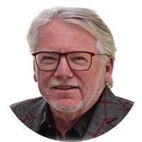 Older white business man wearing black square glasses, a grey plaid suit and black button up