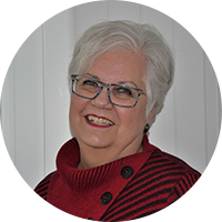 image of an older white woman in glasses wearing a red sweater 