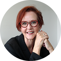Image of an older white woman wearing red glasses and black blouse