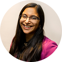 Photo of a south asian business owner wearing glasses and a magenta button up