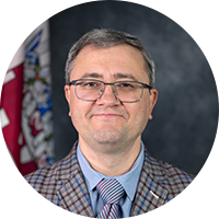 Older white man wearing glasses and a checkered suit