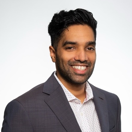 Headshot image of Veda Rajole, he is wearing a black suit with a polka dot shirt.