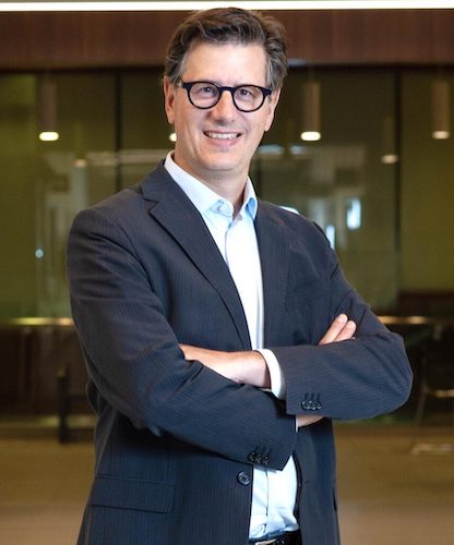 white business man with glasses smiling with his arms crossed